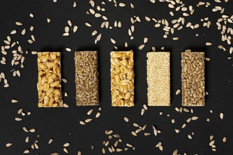 Flat lay cereal bars assortment with sunflower seeds plain background