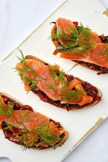 Top view of salmon sandwich with caramelized onion on wooden serving board