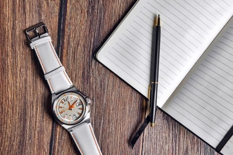 Top view of open blank notebook with pen and wrist watch on wooden table