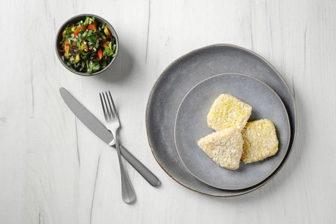 Top view of semifinished squid cutlet in breading on a plate