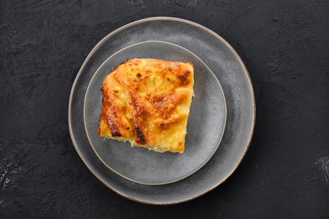 Top view of cheese puff pie from unleavened dough on black wooden background
