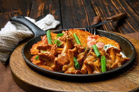 Potato pancakes with chanterelles and pork in cast iron skillet