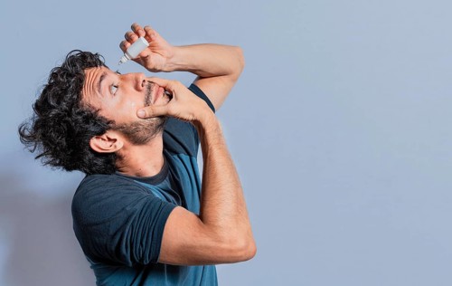 People applying refreshing drops to irritated eye. Man putting a dropper in his eye isolated. Man with irritated eye applying drops with a dropper