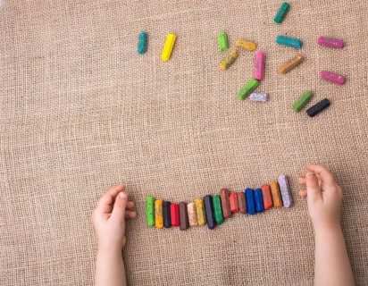 Toddlers hand putting crayons in line on canvas