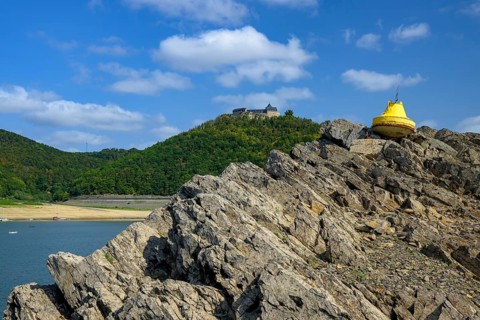 Dry buoy in front of Waldeck Castle at low water in Lake Edersee