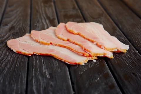 Selective focus photo of slices of fresh bacon on wooden table
