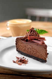 Close up view of piece of chocolate cake with cappuccino