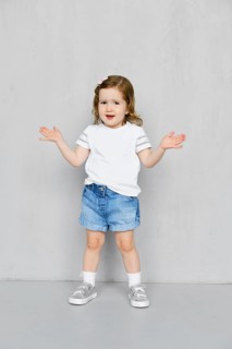 Two years old girl in white t-short and jeans shorts posing in studio