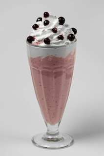 Milkshake black currant summer cocktail in tall facetted glass on gray background