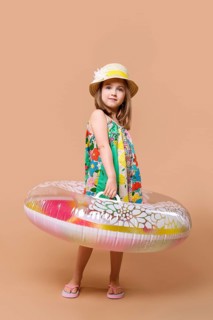Cute child in sundress and straw hat with swimming ring playing in studio