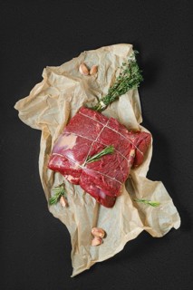 Overhead view of raw beef neck with garlic on wrapping paper