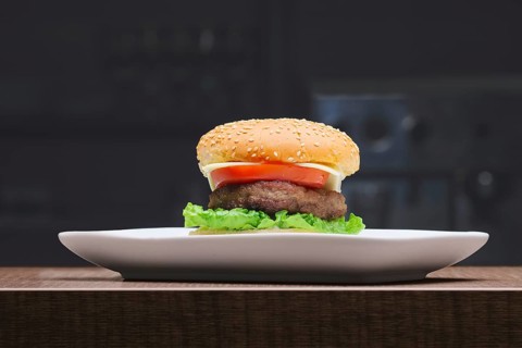 Fresh tasty burger on plate on wooden table