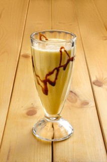 Glass of banana smoothie on wooden table