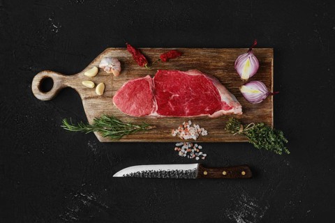 Top view of raw top sirloin beef steak on wooden cutting board