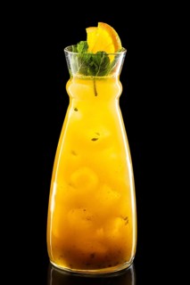 Pitcher with orange and passion fruit ice lemonade isolated on black background