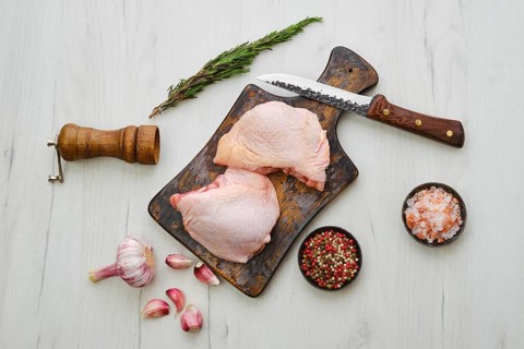 Raw chicken thighs on wooden cutting board ready for cooking