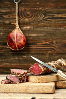 Smoked dried beef meat cut on slices on wooden cutting board