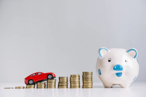 Red car driving increasing stacked coins near piggybank