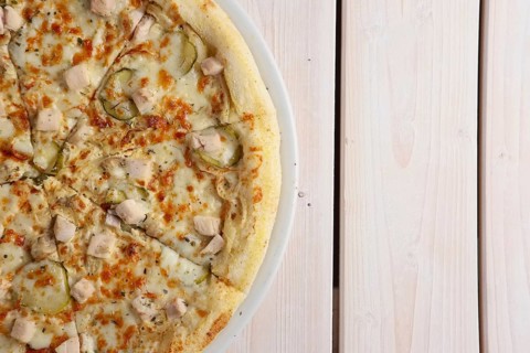 Fresh baked pizza with chicken fillet and pickled cucumber