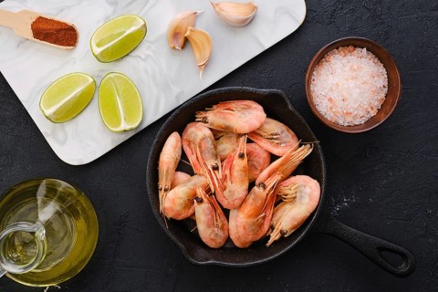 Top view of cast iron skillet with steamed unpeeled shrimps