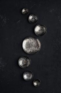 Composition with empty forged bowls of different size on black background