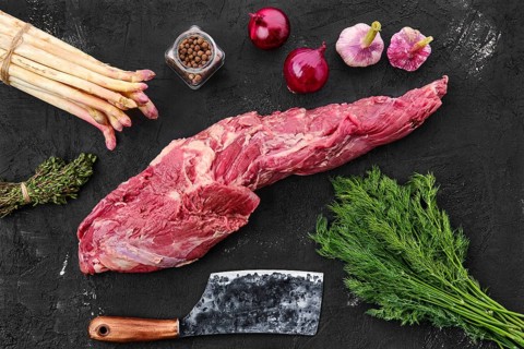 Raw fresh beef whole tenderloin with spice on black background