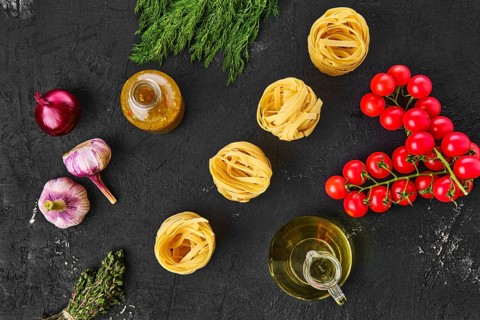 Overhead view of raw tagliatelle with spice and herbs on black background