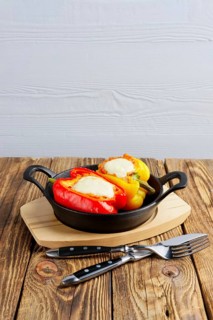 Bell pepper stuffed with meat with melted cheese mozzarella on top baked in oven in cast iron skillet. Top view. Natural wooden background