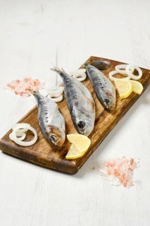 Salted iwashi herring fish marinated in spice on wooden cutting board