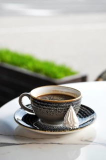 Cup of coffee on the edge of the table on outdoor terrace