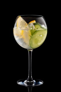 Big round wine glass with fresh cold lemonade isolated on black background