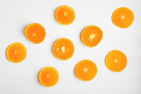Top view of orange slices on white rustic wooden background
