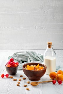 Muesli with apricots and almonds on white wooden table
