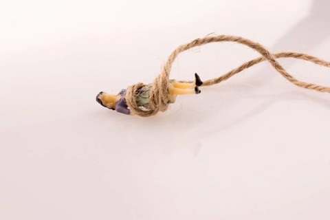 Woman figure lying down tied with a linen thread on a white background