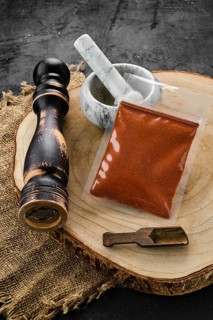 Wooden cross section with chilli pepper in plastic package and stone mortar and mill
