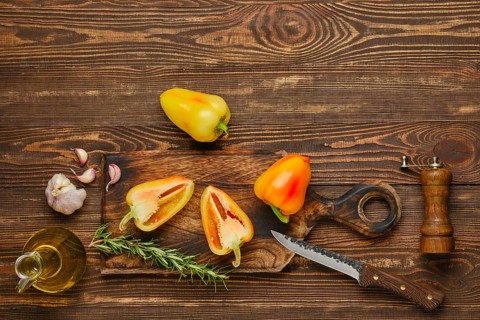 Sweet bell pepper or paprika cut on half and whole on wooden cutting board