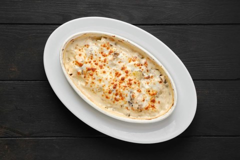 Top view of potato and boletus casserole baked in oven with cheese and bacon
