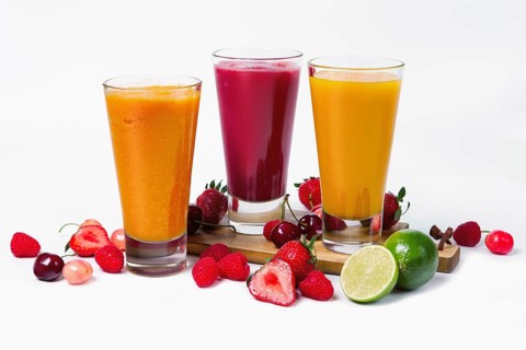 Three glasses with fruit smoothies on white background