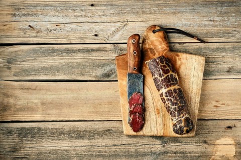 Top view of smoked dried beef meat and slice on wooden cutting board