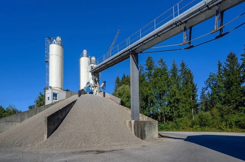 Steel silos and shovel crane with gravel piles and conveyor belt