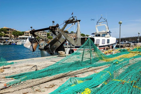Fishing nets lying stretched out to dry for repair on quay at harbour pier