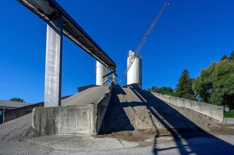 Steel silos and shovel crane with gravel piles and conveyor belt