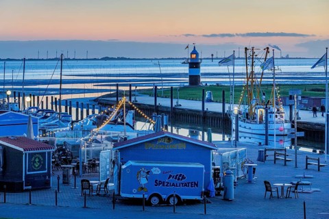 Sielhafen with stalls and lighthouse Kleiner Preusse at the mouth of the Weser at dusk