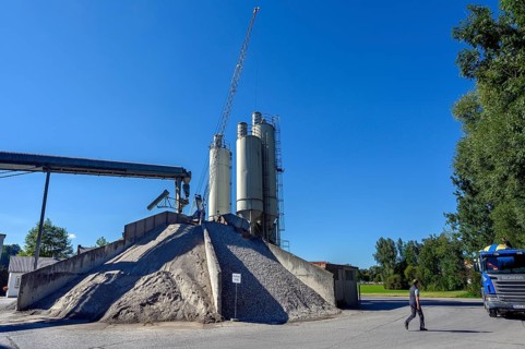 Steel silos and shovel crane with gravel piles and conveyor belt