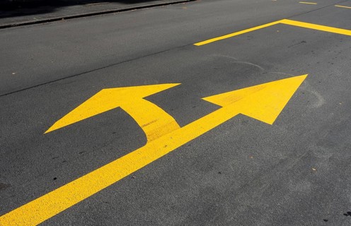 Yellow marking arrow on a road for straight ahead and left turn