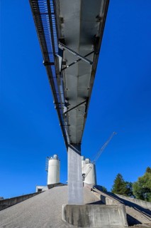 Steel silos and shovel crane with gravel piles and conveyor belt