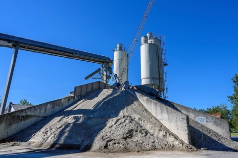 Steel silos and shovel crane with gravel piles and conveyor belt