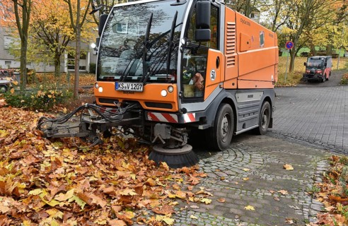 Sweeper sweeps up wilted leaves in autumn
