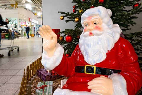 Father Christmas waving to passers-by with shopping trolley