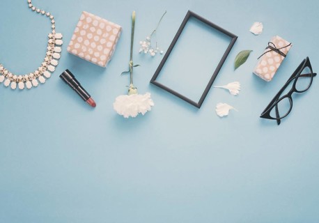 Blank frame with flowers gift boxes lipstick table